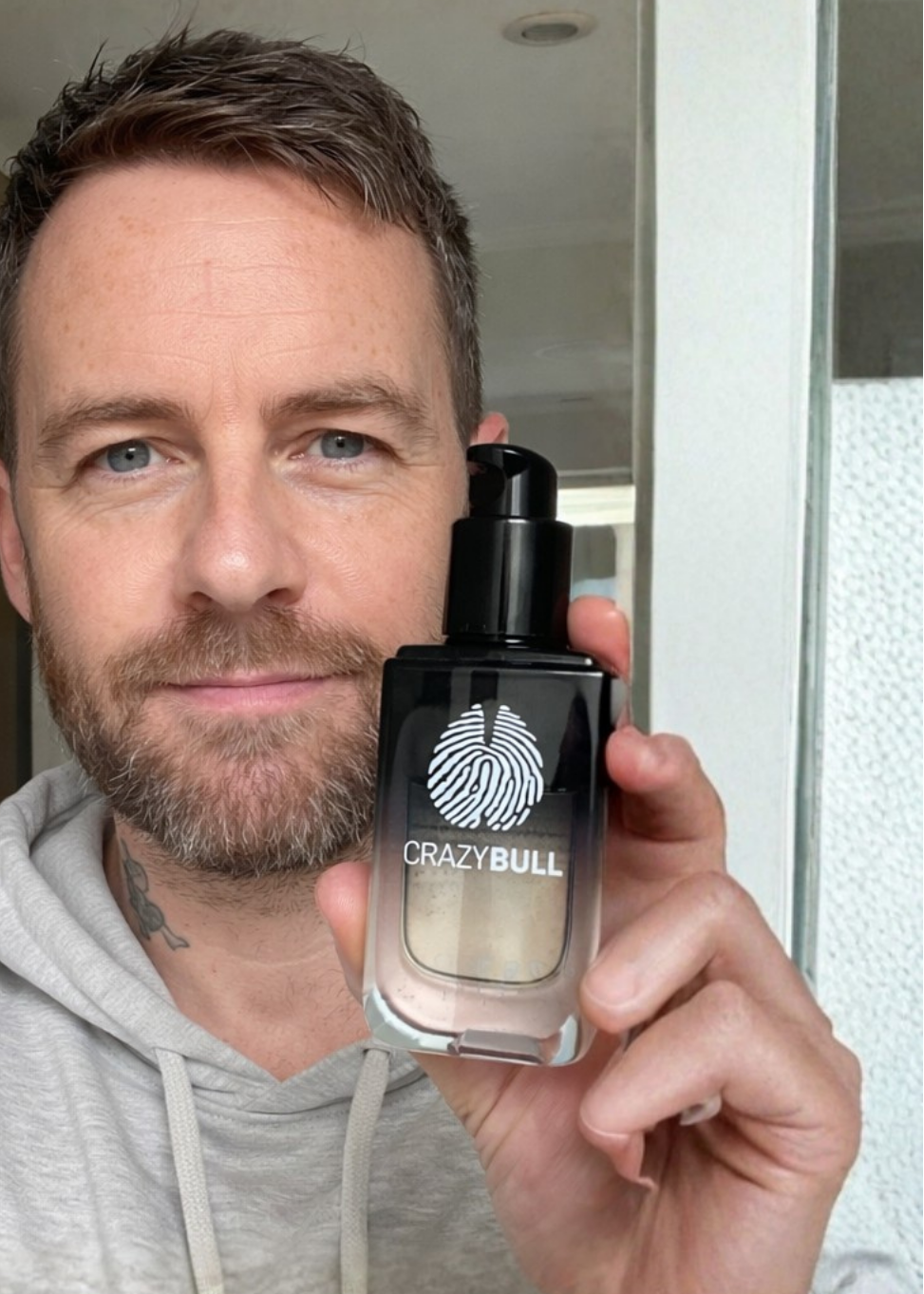 Man holding a bottle of 'Crazy Bull' product in front of a mirror.