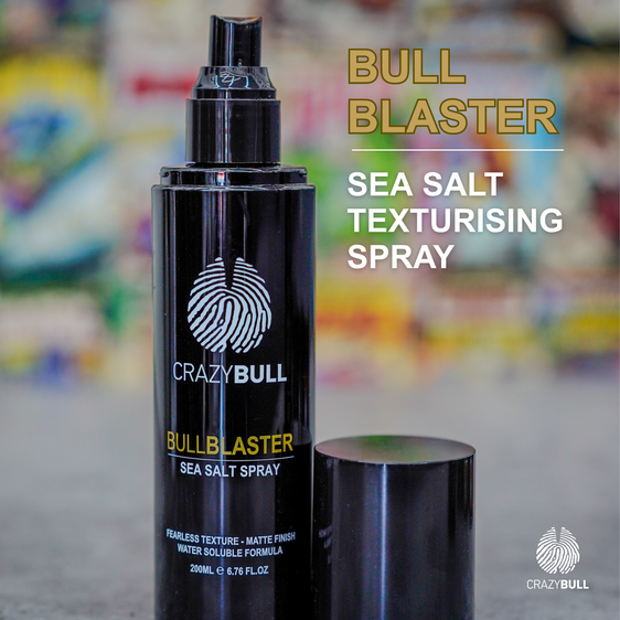 Black spray bottle labeled 'Crazy Bull Bull Blaster Sea Salt Spray' on a blurred background